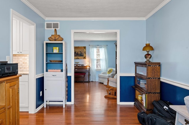 interior space with crown molding, light countertops, wood finished floors, and visible vents