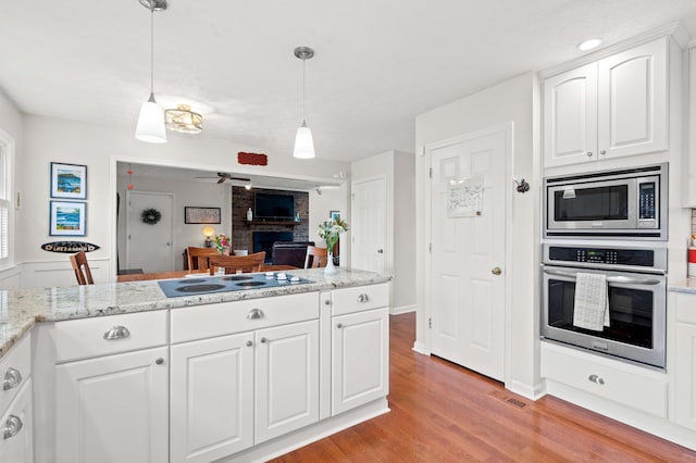 kitchen with visible vents, pendant lighting, white cabinets, light wood finished floors, and appliances with stainless steel finishes