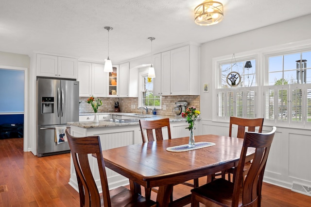 dining area with arched walkways, light wood finished floors, and visible vents