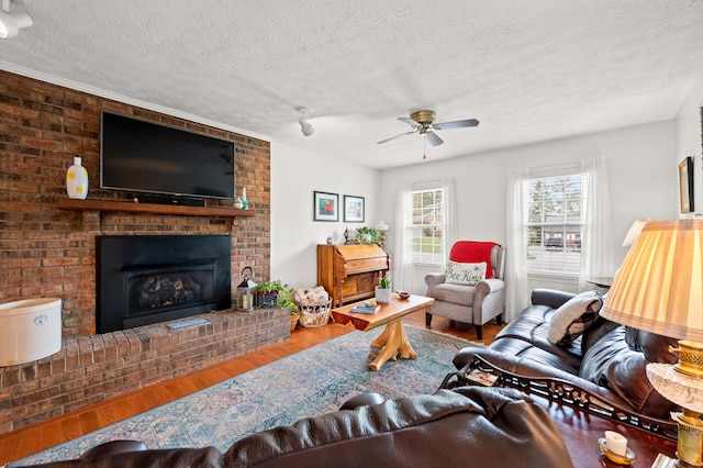 living area featuring a textured ceiling, ceiling fan, wood finished floors, and a fireplace