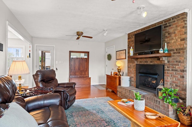 living area featuring baseboards, ceiling fan, wood finished floors, and a fireplace