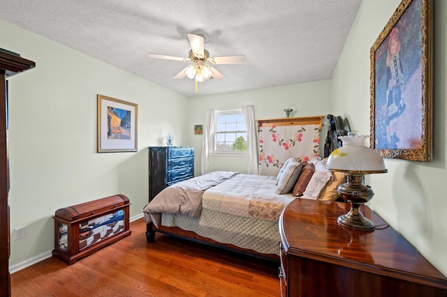 bedroom with baseboards, a textured ceiling, ceiling fan, and wood finished floors