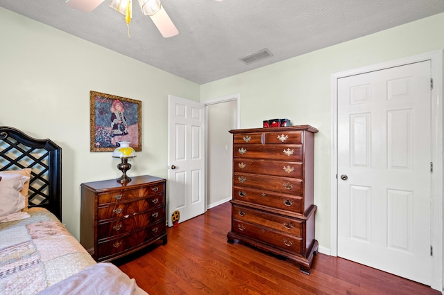 bedroom with a ceiling fan, wood finished floors, and visible vents