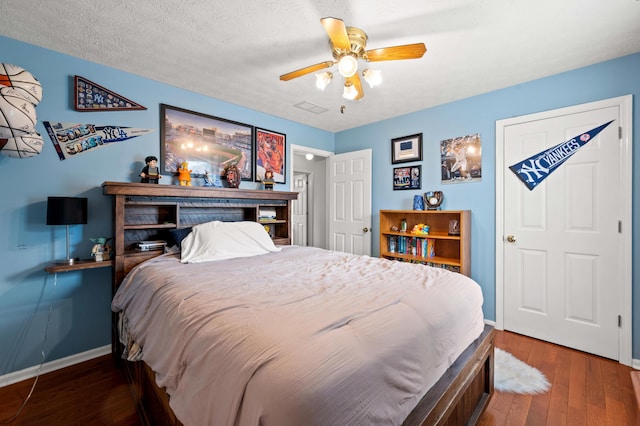 bedroom with a ceiling fan, baseboards, visible vents, and hardwood / wood-style floors