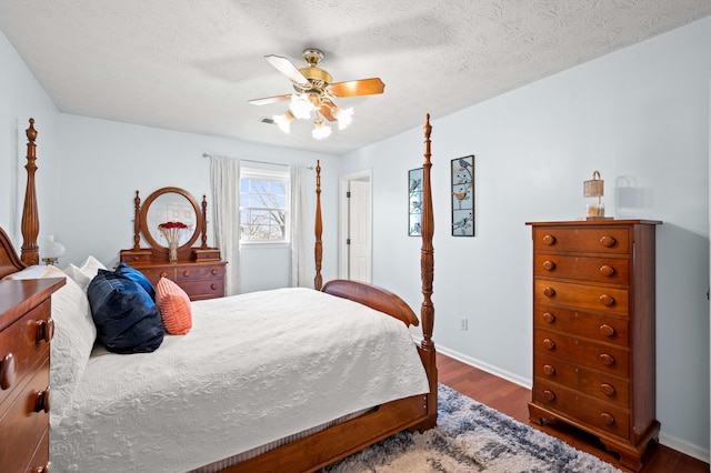 bedroom featuring ceiling fan, a textured ceiling, baseboards, dark wood-type flooring, and visible vents