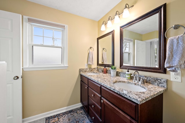 bathroom with double vanity, baseboards, and a sink
