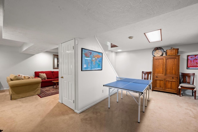 rec room with a textured ceiling, baseboards, and light carpet
