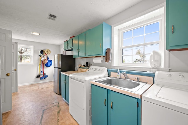 laundry area featuring separate washer and dryer, a textured ceiling, visible vents, and a sink