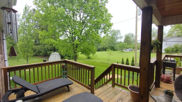 wooden terrace with a lawn, an outdoor structure, a shed, and a fenced backyard