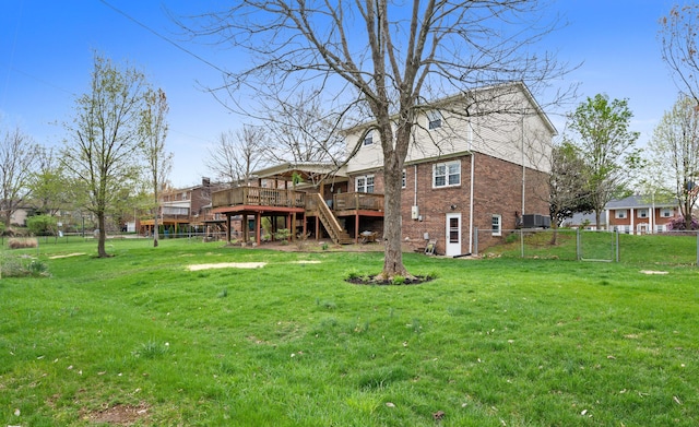back of house featuring fence, stairs, brick siding, a deck, and a lawn