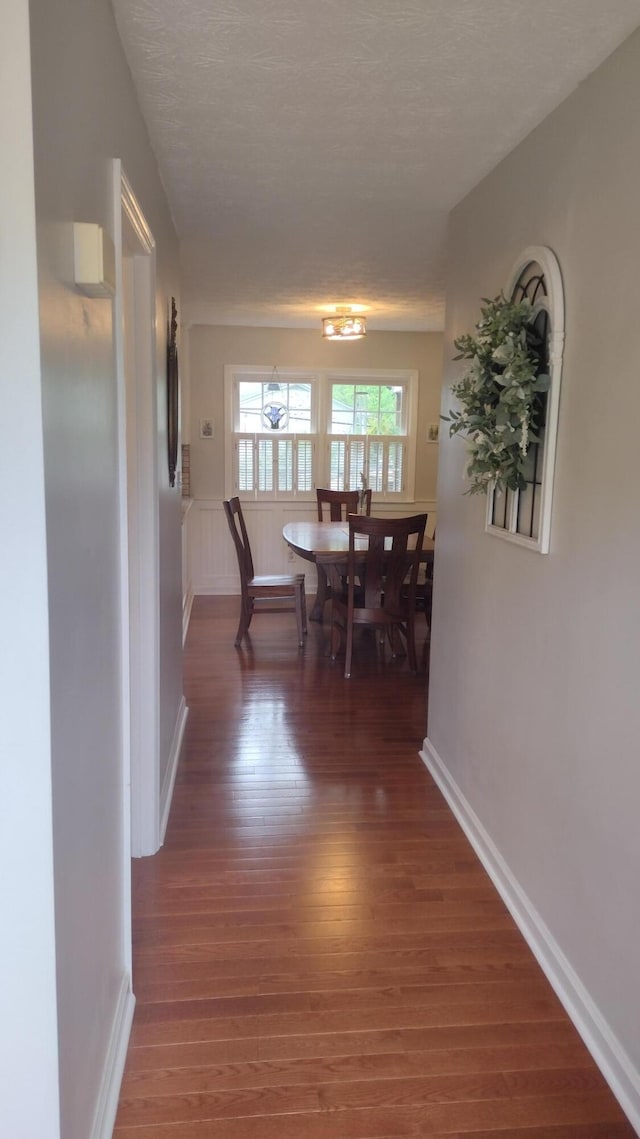 dining space featuring baseboards, a textured ceiling, and wood finished floors