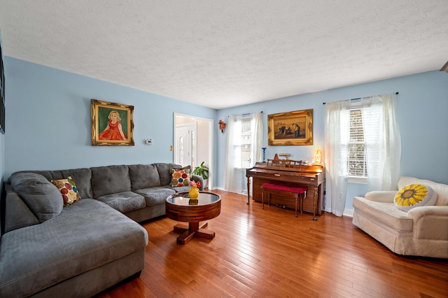 living room with baseboards, a textured ceiling, and hardwood / wood-style flooring