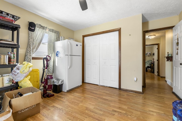 misc room featuring light wood-style floors, ceiling fan, and a textured ceiling