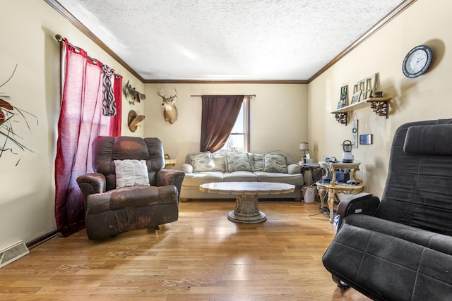 living room with visible vents, ornamental molding, a textured ceiling, and light wood-style flooring