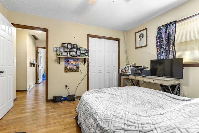 bedroom featuring ceiling fan, visible vents, baseboards, a closet, and light wood finished floors