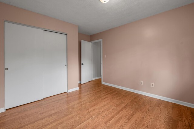 unfurnished bedroom with light wood-type flooring, baseboards, and a closet