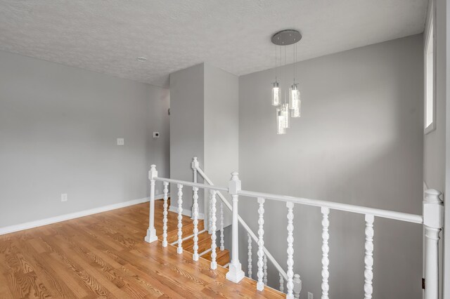 stairway featuring wood finished floors, a textured ceiling, and baseboards