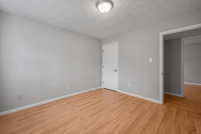 unfurnished bedroom featuring a textured ceiling, light wood-style floors, and baseboards