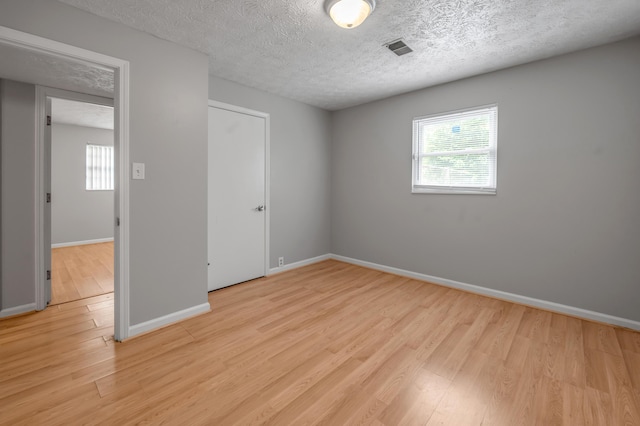 unfurnished bedroom featuring light wood-style floors, baseboards, and a textured ceiling