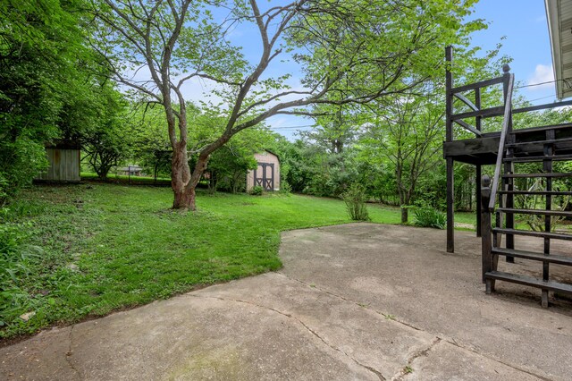 view of grassy yard featuring a patio area, a storage unit, stairs, and an outdoor structure