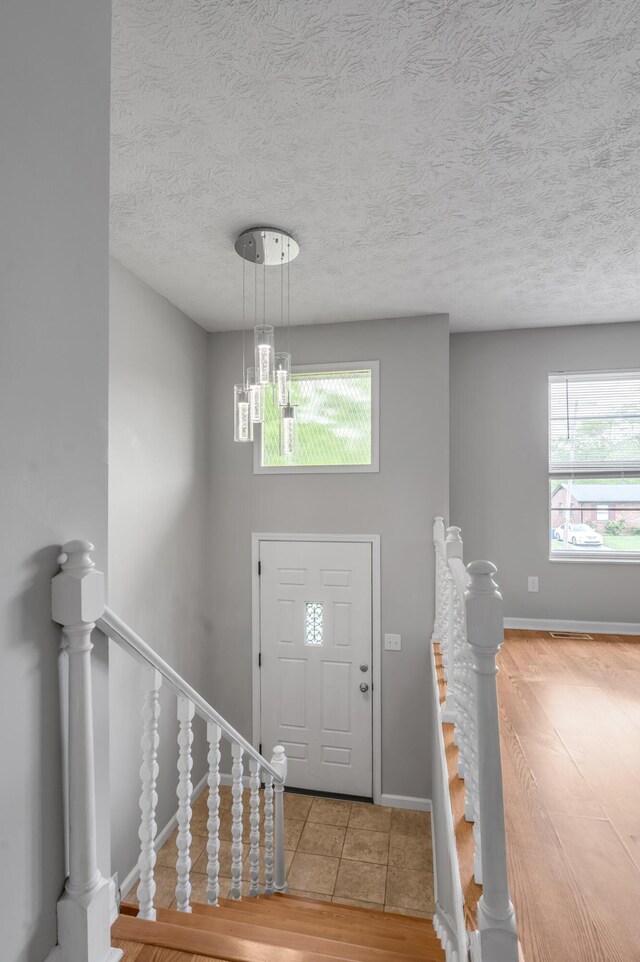 entryway with wood finished floors, baseboards, and a textured ceiling