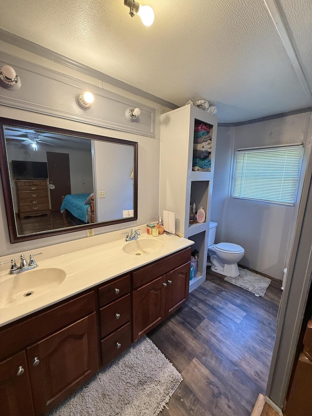 full bath with a sink, a textured ceiling, and wood finished floors