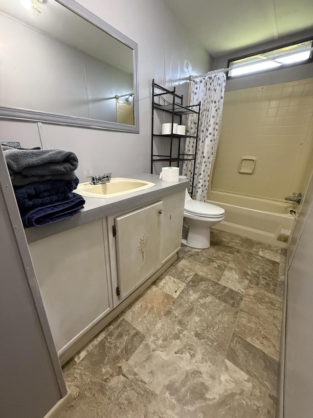 bathroom with vanity, stone finish flooring, shower / tub combo, and toilet
