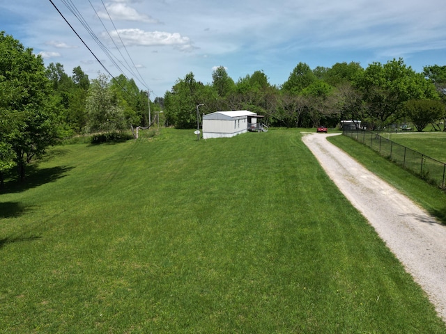 view of yard with fence and dirt driveway