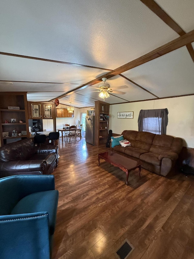 living area with ceiling fan, a textured ceiling, visible vents, wood finished floors, and beamed ceiling