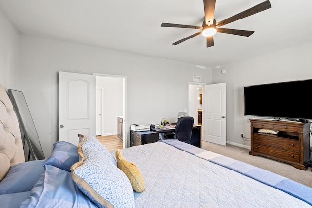 bedroom with baseboards, a ceiling fan, ensuite bathroom, and light carpet