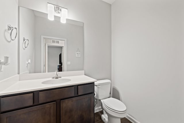 bathroom featuring vanity, visible vents, wood finished floors, toilet, and baseboards