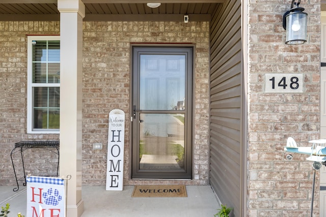 property entrance with covered porch and brick siding