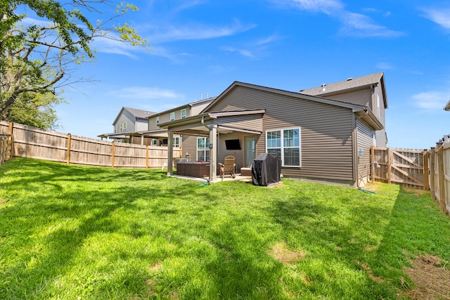 back of house with a hot tub, a patio, a fenced backyard, and a lawn