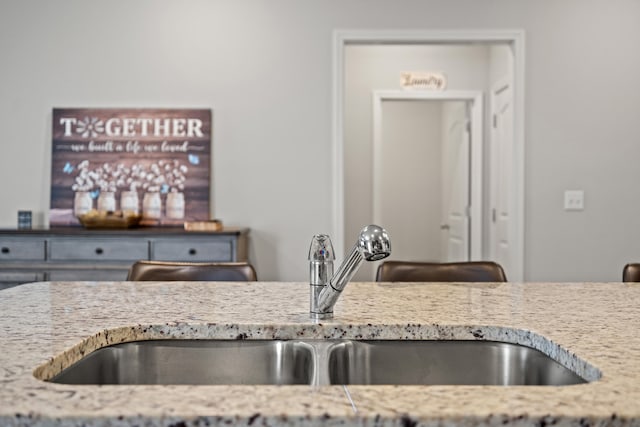 kitchen with light stone counters and a sink