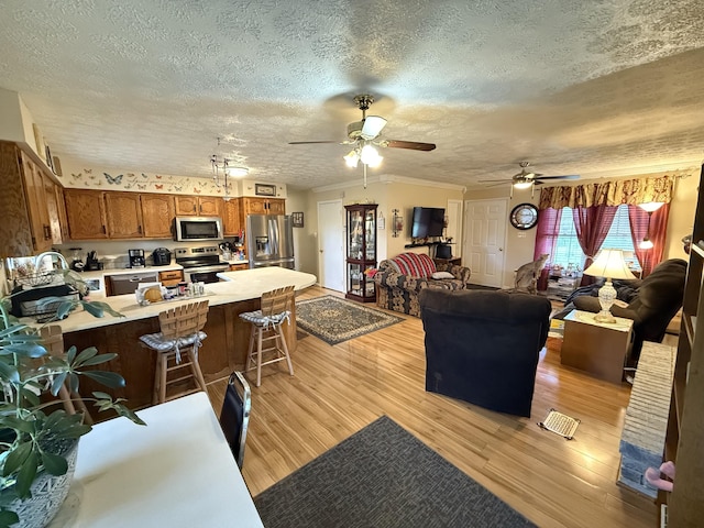 living room featuring a ceiling fan, a textured ceiling, and light wood-style flooring