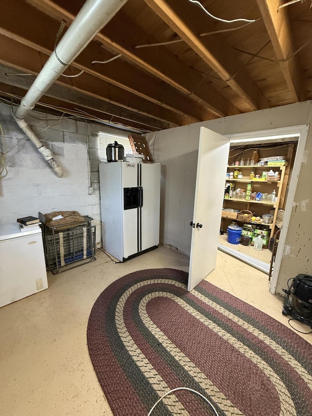 unfinished below grade area with white fridge with ice dispenser and fridge