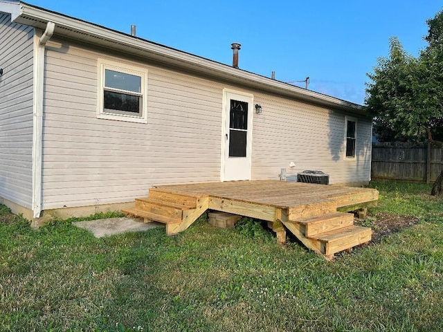 rear view of property featuring a wooden deck, a yard, and fence