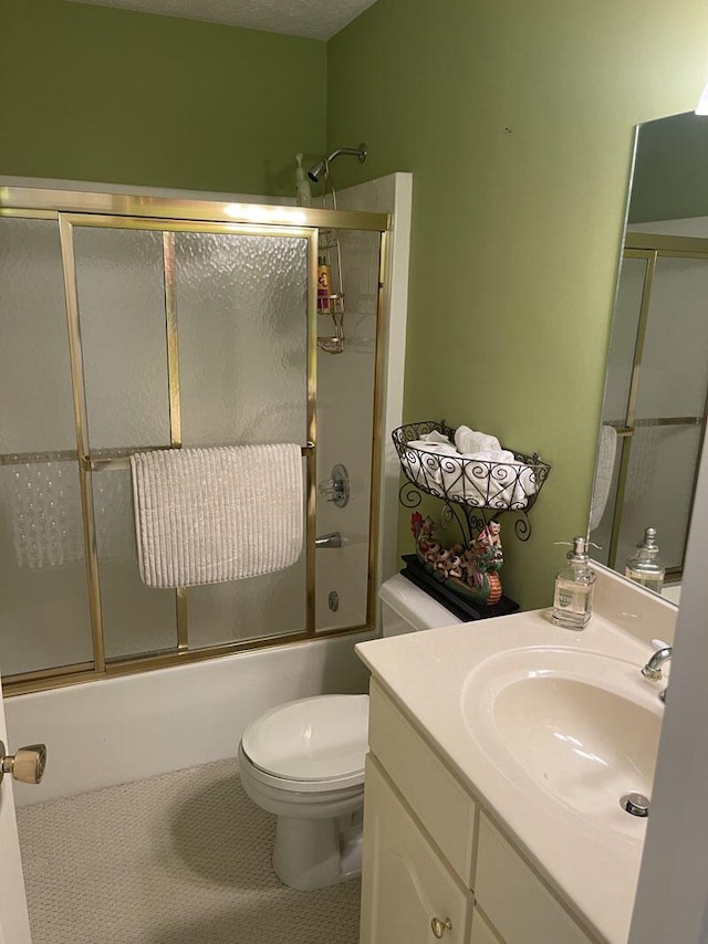 full bathroom featuring vanity, tile patterned flooring, combined bath / shower with glass door, and toilet