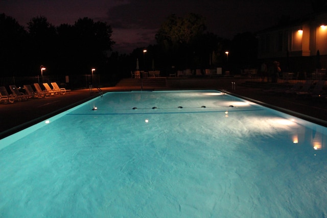 pool at twilight featuring a patio and a community pool