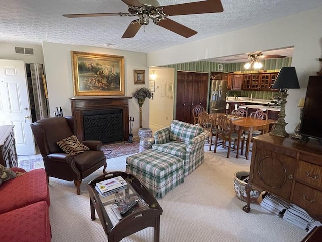 living room featuring visible vents, a textured ceiling, ceiling fan, and a fireplace