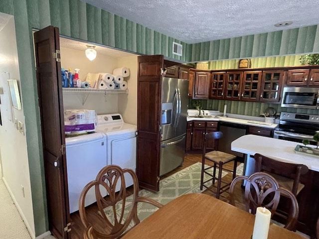 kitchen featuring a textured ceiling, independent washer and dryer, visible vents, appliances with stainless steel finishes, and light countertops