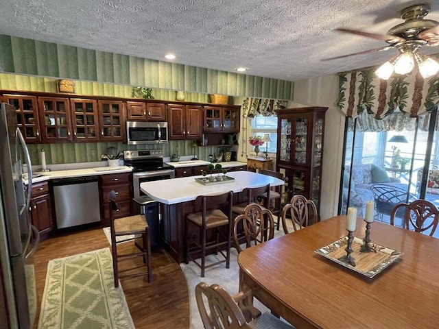 kitchen featuring ceiling fan, a textured ceiling, light wood-type flooring, light countertops, and stainless steel appliances