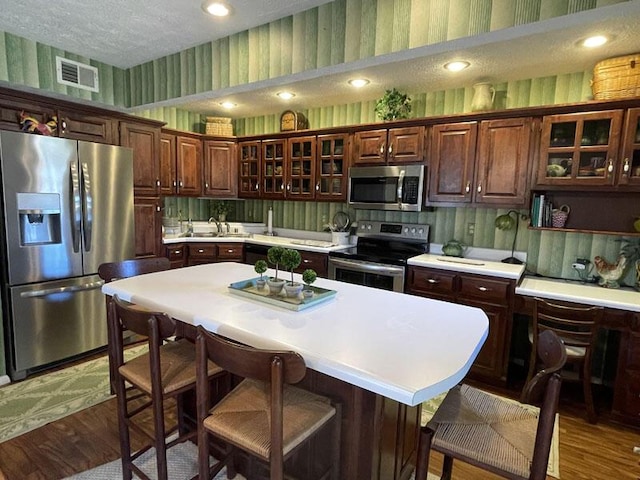 kitchen with visible vents, a breakfast bar area, wallpapered walls, light countertops, and appliances with stainless steel finishes