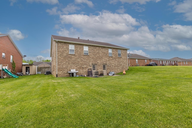back of property with a lawn, a storage unit, and brick siding