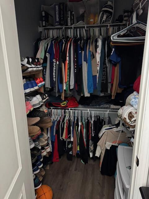walk in closet with wood finished floors