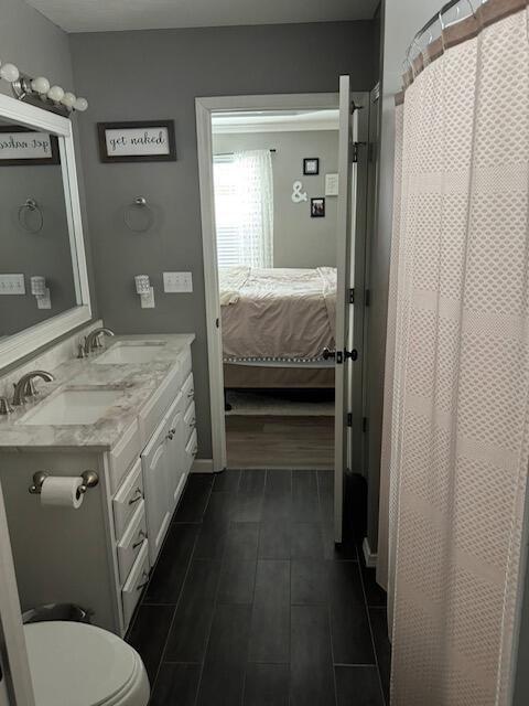 ensuite bathroom featuring a sink, ensuite bathroom, toilet, and double vanity