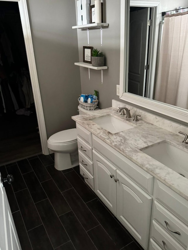 bathroom featuring a sink, tile patterned floors, toilet, and double vanity