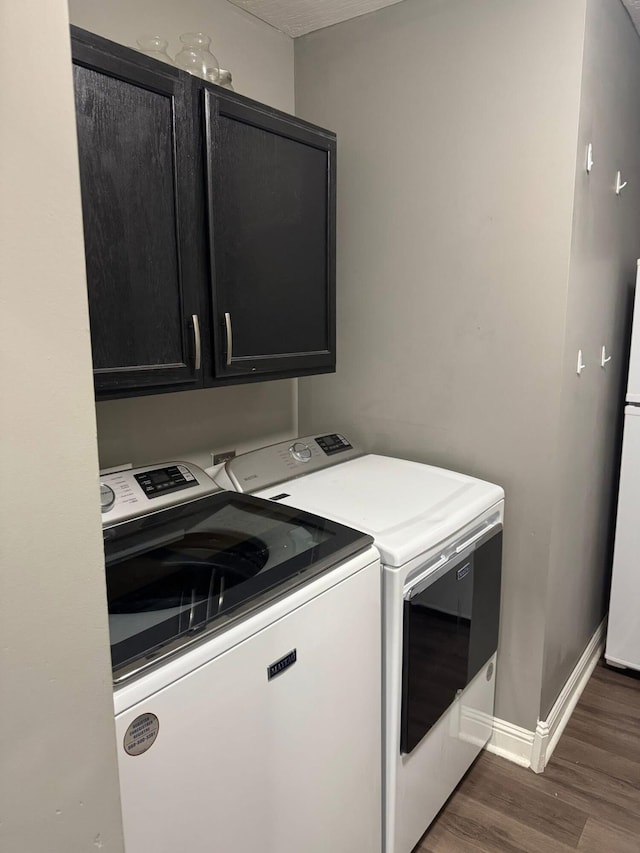 washroom with baseboards, cabinet space, washing machine and dryer, and wood finished floors