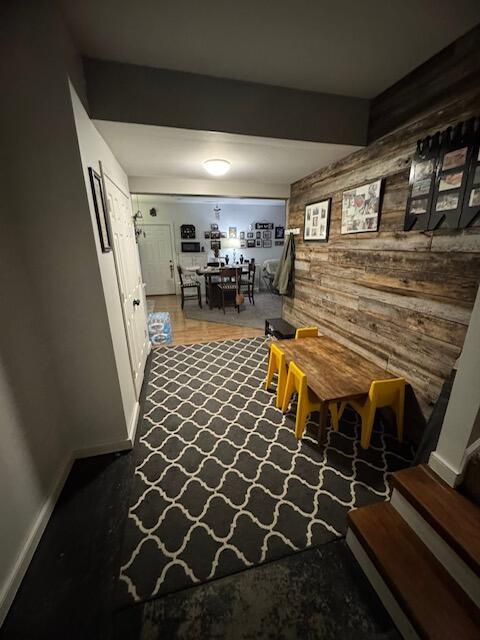 dining room with baseboards, wood walls, and an accent wall