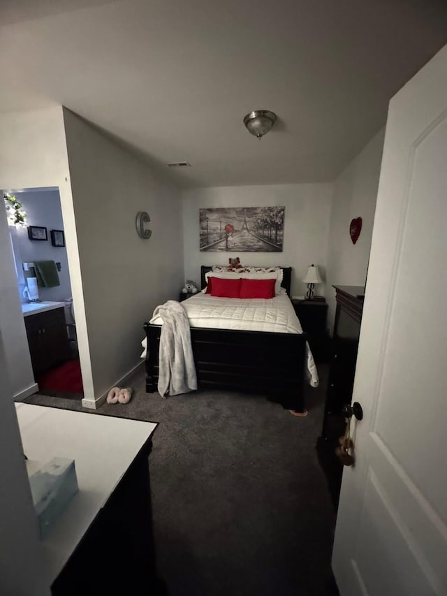 bedroom with carpet floors, ensuite bathroom, baseboards, and visible vents